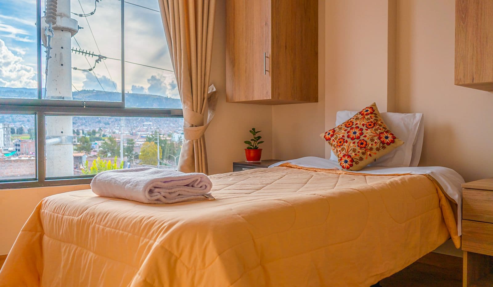 Quarto iluminado com a cama arrumada e vista da cidade